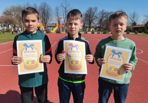 3 chłopcy z dyplomami - zwycięzcy klasowego biegu wielkanocnego.
