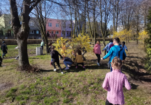 Dzieci biegną w szkolnym ogrodzie, szukają upominków od wielkanocnego zajączka.