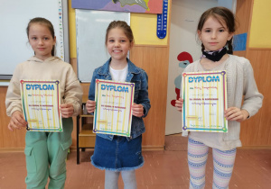 3 dziewczynki - zwyciężczynie konkursu z klas II - trzymają w rękach dyplomy.