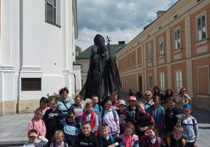 Uczniowie stoją przy pomniku Św. Jana Pawła II w Wadowicach.