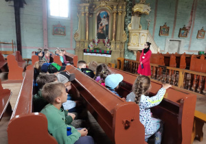 Uczniowie słuchają opowiadania przewodnika w starym kościele.