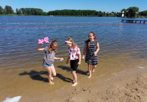 3 dziewczynki spacerują na brzegu zalewu.