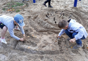 Dzieci tworzą swoje budowle z piasku.