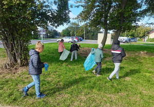 Dzieci sprzątają teren wokół szkoły.