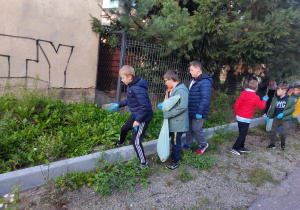 Dzieci sprzątają teren wokół szkoły.