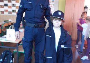Chłopiec ubrany w policyjną kurtkę i czapkę