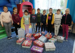 Dziewięcioro dzieci stoi za przygotowanymi przez siebie prezentami