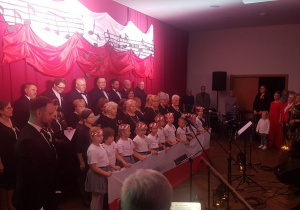 Dzieci trzymając polską flagę śpiewają hymn Mazurek Dąbrowskiego.