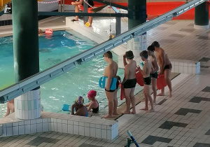 Dzieci trenują pływanie na małym basenie.