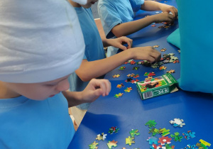 Uczniowie biorą udział w konkursie układania smerfnych puzzli.