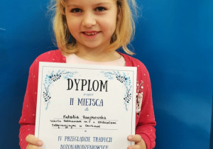 Dziewczynka pokazuje dyplom konkursowy.