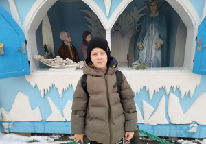 Chłopiec pozuje przy lodowym domku.