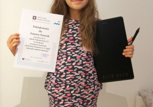 Dziewczynka trzyma dyplom i nagrodę