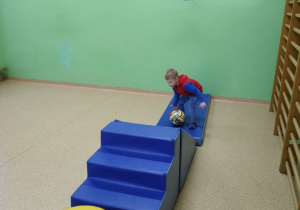Dziecko odwiedzające szkołę bawi się w sali gimnastycznej.