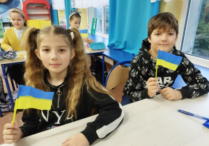 Uczniowie prezentują wykonane własnoręcznie chorągiewki ukraińskie.