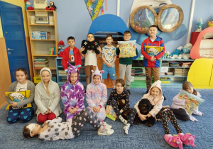 Dzieci pozują w piżamach na dywanie w klasie.