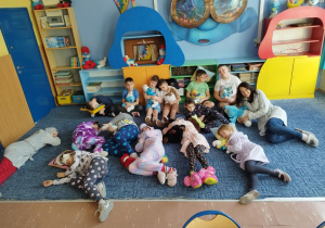 Dzieci pozują w piżamach na dywanie w klasie.