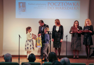 Wiktoria odbiera nagrodę z rąk wicemarszałka województwa łódzkiego.