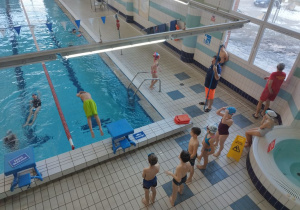 Uczniowie trenują skoki do basenu.