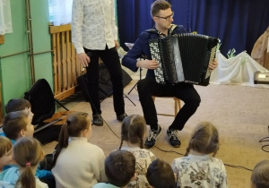 Nauczyciel gra na akordeonie guzikowym.