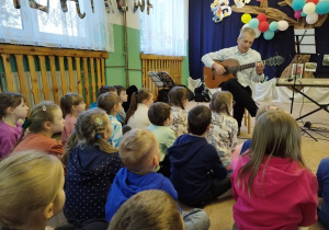 Nauczyciel gra na gitarze klasycznej.