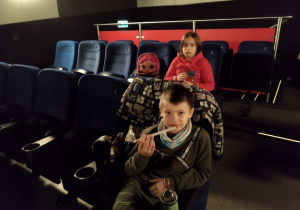 Uczniowie czekają na projekcję filmu w sali kinowej.