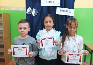 Uczniowie z klasy II A trzymają dyplomy uczestnictwa w konkursie "Bajkoludki lubią wiersze"