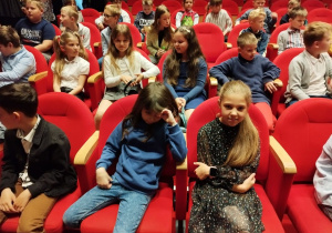 Dzieci siedzą na widowni, czekają na spektakl pt. "Calineczka".