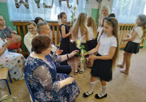 Trzecioklasiści wręczają kwiaty zaproszonym gościom