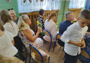 Trzecioklasiści wręczają kwiaty zaproszonym gościom