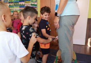 Chłopcy z klasy II B przyklejają kropki na odzież nauczycielki