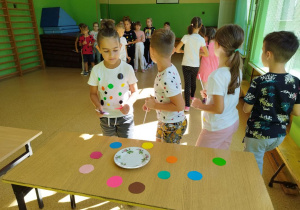 Uczniowie z klasy II B umieszczają swoje kropki na talerzu za pomocą słomki