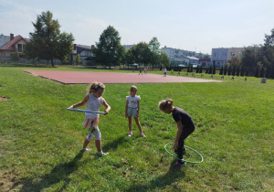 Dziewczynki kręcą kołami hula-hoop.