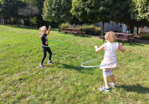 Dziewczynki kręcą kołami hula-hoop.
