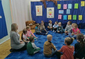 Dzieci słuchają czytanej przez panią bibliotekarkę bajki o przygodach Bolka i Lolka.