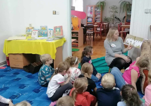 Dzieci słuchają czytanej przez panią bibliotekarkę bajki o przygodach Bolka i Lolka.