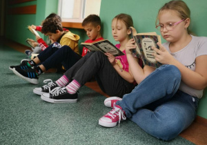 Uczniowie z klasy II B czytają lekturę podczas przerwy.