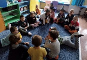 Dzieci opowiadają historyjkę siedząc na dywanie.
