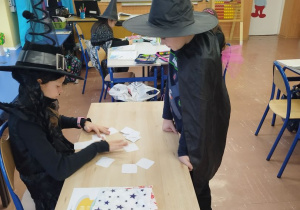 Uczennica w stroju czarownicy "przepowiada przyszłosć" za pomocą kart