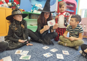 Pani wróży ze śmiesznych magicznych kart dzieciom siedzącym w kole na dywanie