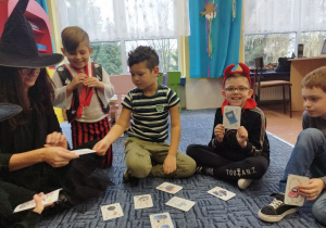 Pani wróży ze śmiesznych magicznych kart dzieciom siedzącym w kole na dywanie