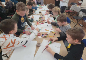Uczniowie malują farbami gipsowe figurki świąteczne.