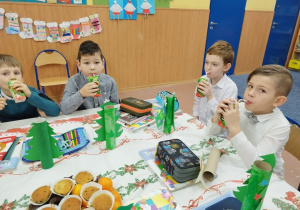 Dzieci jedzą świąteczne smakołyki i owoce
