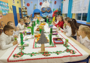 Dzieci jedzą świąteczne smakołyki i owoce