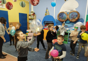 Dzieci tańczą z balonikami na dywanie w klasie