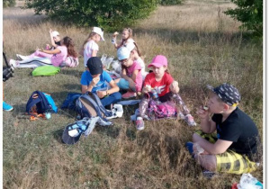 Grupa dzieci z klasy II siedzi na trawie