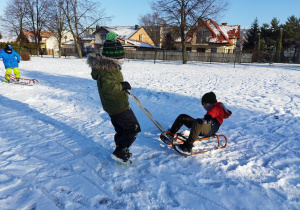 Zimowe zabawy na boisku szkolnym - wyścigi saneczkowe.