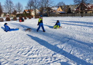 Zabawy na śniegu na boisku szkolnym - wyścigi saneczkowe.