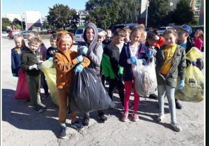 Grupa dzieci z workami wypełnionymi śmieciami