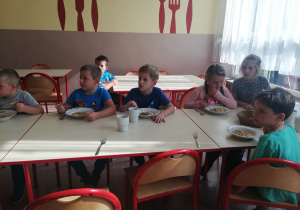 Kilkoro uczniów je obiad w szkolnej stołówce